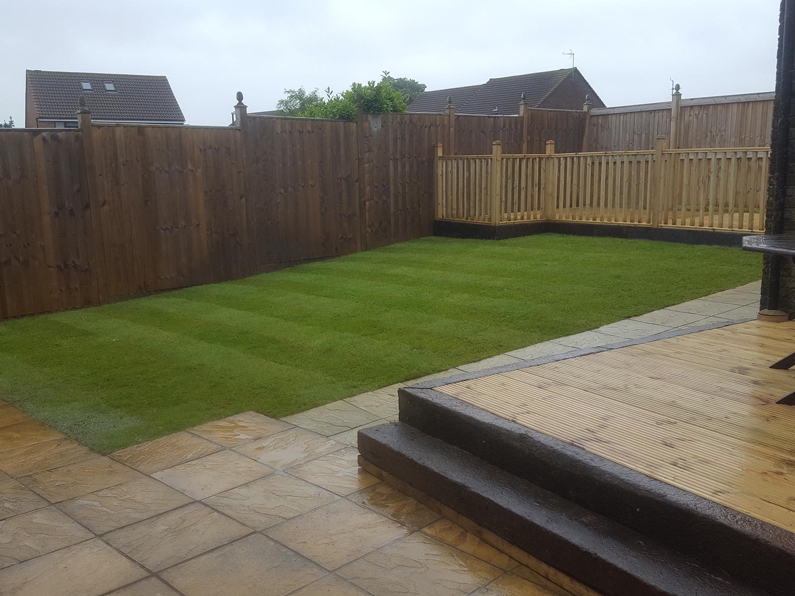 Sleeper edged decking with newly layed turf lawn.
